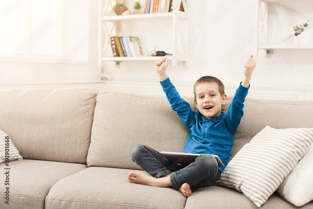 Little boy using digital tablet on sofa at home