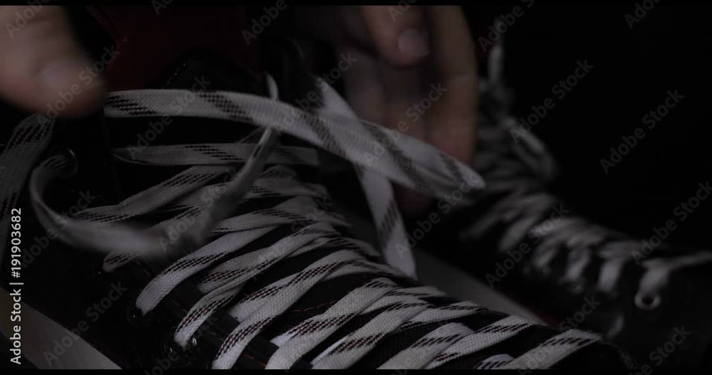 A player in hockey, ties laces on skates, a black background. A player in hockey, ties laces on skates, a black background.