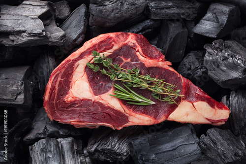 Raw fresh meat Ribeye steak on black charcoal background photo