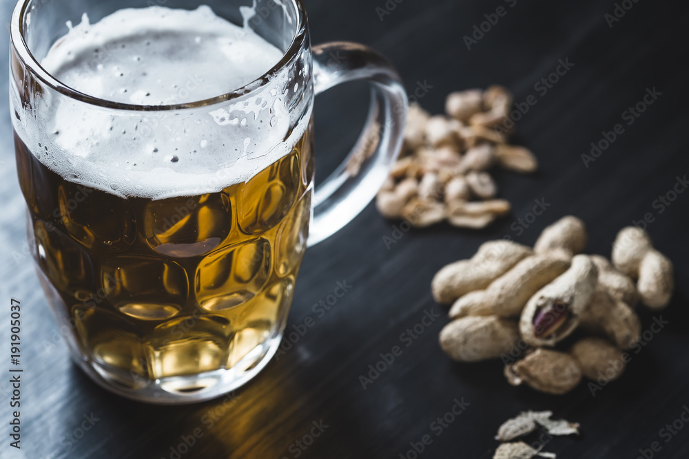 Glass of beer and peanuts on the wooden background Glass of beer and peanuts on the wooden background