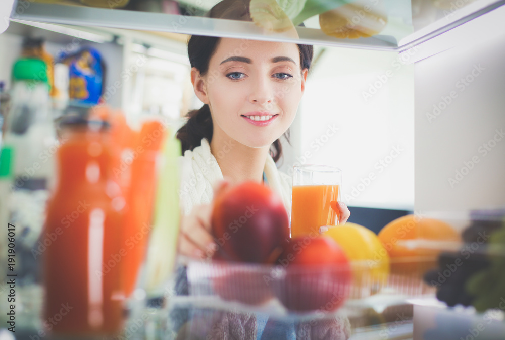 Portrait of female standing near open fridge full of healthy food, vegetables and fruits. Portrait of female Portrait of female standing near open fridge full of healthy food, vegetables and fruits. Portrait of female