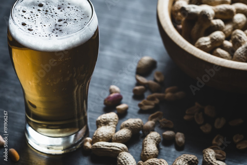 Glass of beer and peanuts on the wooden background