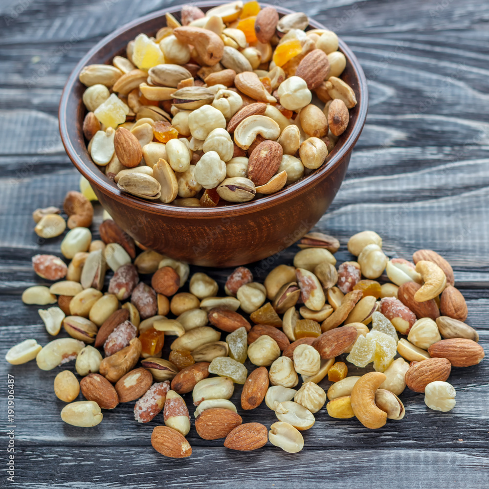 Mix nuts in earthenware on a wooden background. Mix nuts in earthenware on a wooden background.