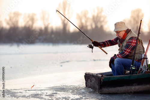 elderly man fishing in the winter on the lake