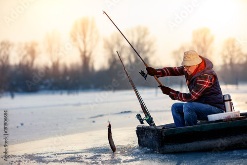 Happy fisherman catch fish on the frozen river in winter