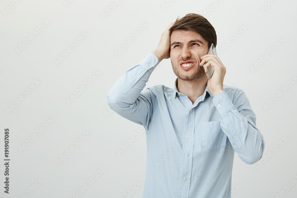 Portrait of charming european male covering mouth with hands, lifting eyebrows and expressing shock and surprise, standing against gray background. I accidentally deleted important data Portrait of charming european male covering mouth with hands, lifting eyebrows and expressing shock and surprise, standing against gray background. I accidentally deleted important data