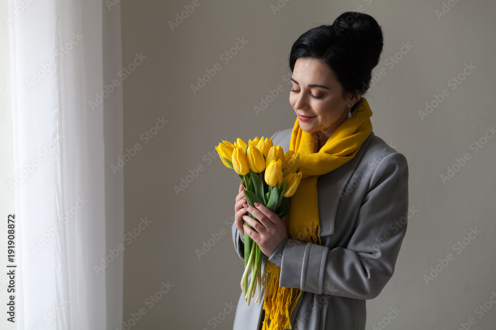girl with yellow tulips stands at the window in the room girl with yellow tulips stands at the window in the room