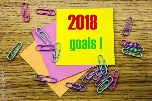 2018 goals on yellow sticky note, on wooden background. New Year resolutions concept. photo