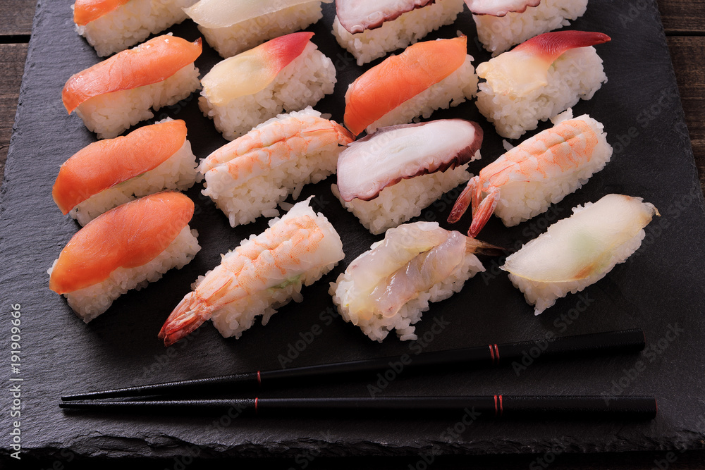Sushi japanese japan food various selection raw fish salmon prawn shrimp in a row line on a black slate tray or platter photo