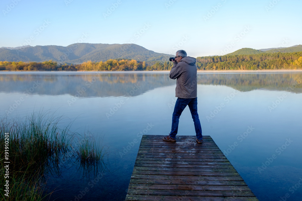Fototapeta premium man taking photos standing on a pier