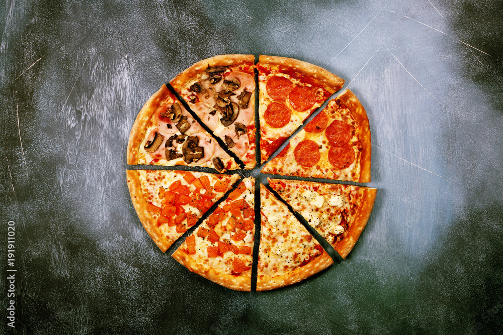 Slices of pizza with different toppings on a dark textured background