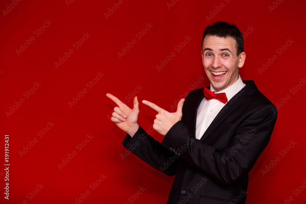 Young Stylish man in suit pointing finger and looking in camera. Photo for business projects, product presentation. Image with copy space isolated on red Young Stylish man in suit pointing finger and looking in camera. Photo for business projects, product presentation. Image with copy space isolated on red