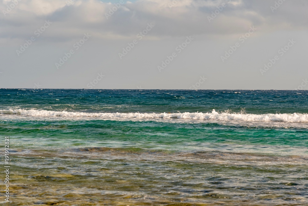 pebble beach and ocean waves on the sea of the Caribbean island of Aruba