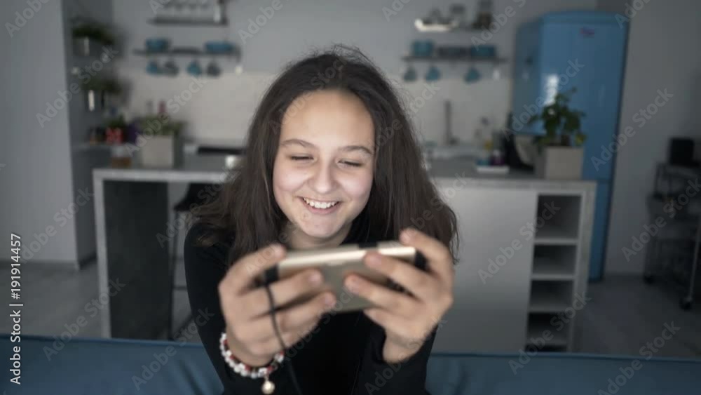 Happy teenage girl texting on smartphone sitting on sofa at home
Happy teenage girl texting on smartphone sitting on sofa at home