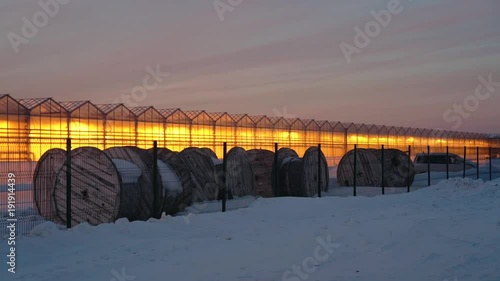 glowing greenhouses against the backdrop of a sunset in winter