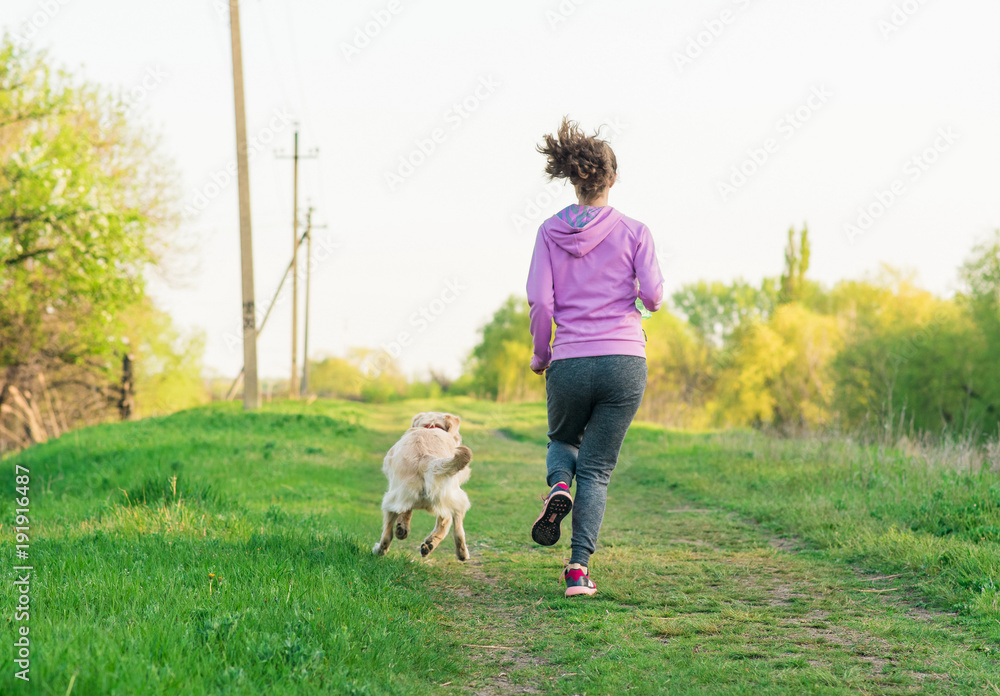 Young pretty girl running outdoor in the spring with dog Young pretty girl running outdoor in the spring with dog