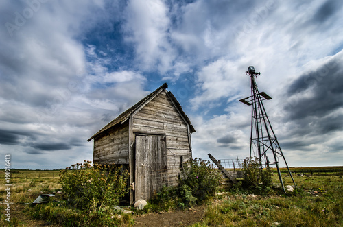 OLD WEATHER BEATEN SHACK AND BROKEN PRAIRIE WIND MILL