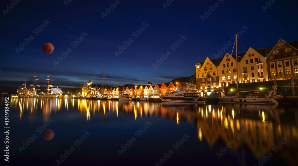 A night long exposure photography of Bergen at harbor  with beautiful water reflection of full blue moon