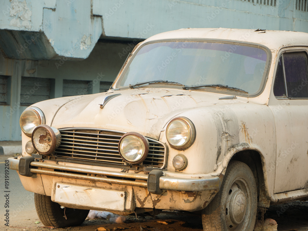 Rusty white car parked on a street of Chennai, India