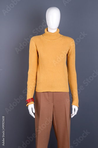 Women brand apparel on mannequin. Warm pullover and brown trousers for women. Ladies clothes boutique.