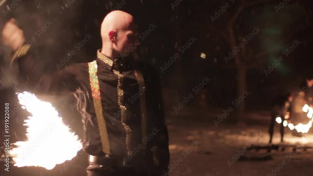 Amazing tribal fire show dance at night on winter under falling snow. Dance group performs with torch lights and pyrotechnics on snowy weather. Amazing tribal fire show dance at night on winter under falling snow. Dance group performs with torch lights and pyrotechnics on snowy weather.