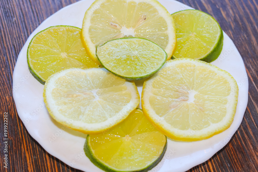 Lemon and lime slices close-up. Citrus on plates. Yellow with green. Lemon and lime slices close-up. Citrus on plates. Yellow with green.