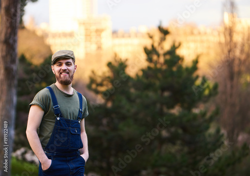 Handsome smiling bearded man in green hat in garden