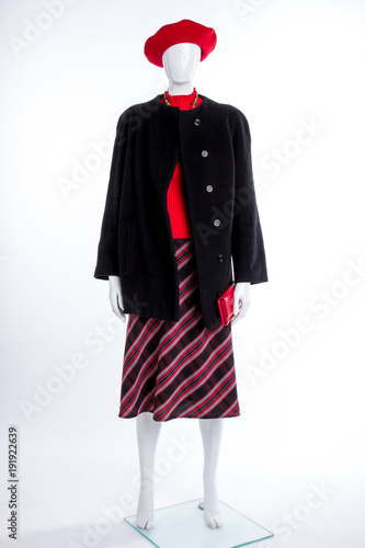 Red beret and black coat for women. Female mannequin dressed in black top coat and skirt, isolated on white background. Ladies fashion and style.