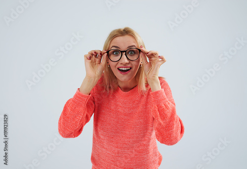 surprised blond in sweater holding glasses