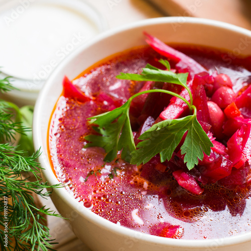 Borscht-vegetable beetroot soup, on the table with slices of rye cereal bread and gluten of sour cream, garlic and herbs. Rustic style. photo