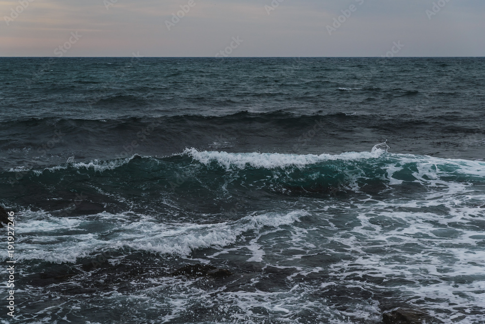 Storm on the sea in cloudy weather at sunset