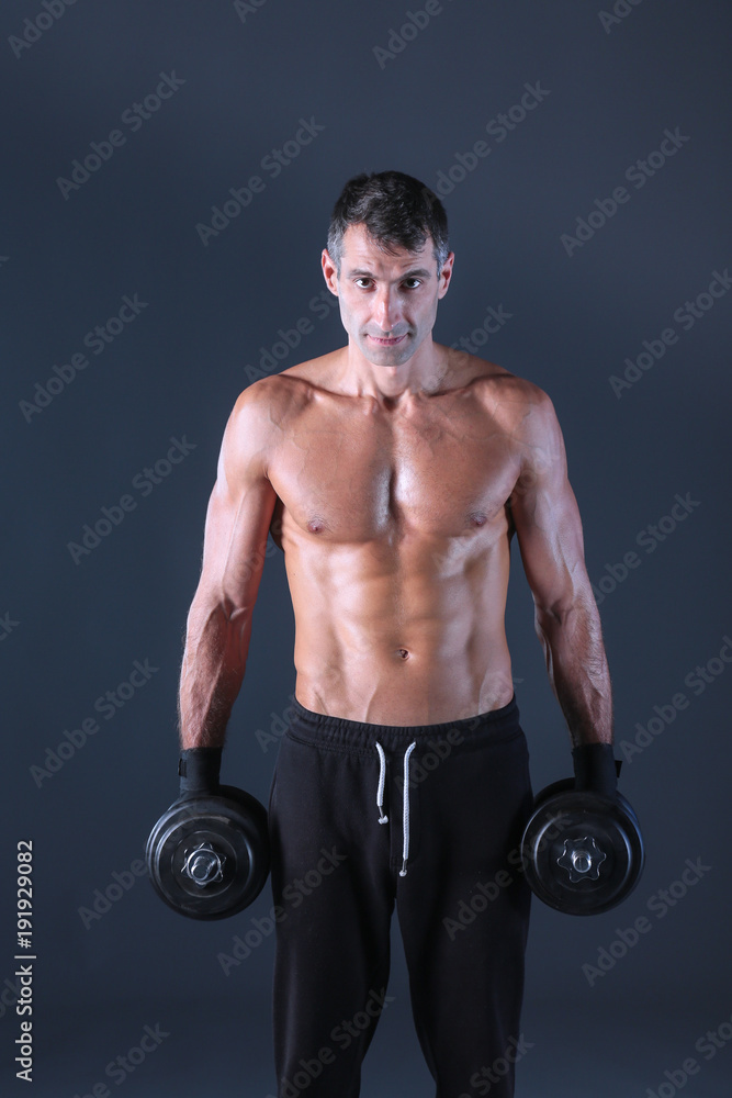 Handsome muscular man working out with dumbbells. Personal fitness instructor. Personal training. Handsome muscular man working out with dumbbells. Personal fitness instructor. Personal training.