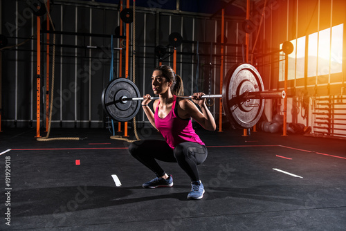 Athletic girl works out at the gym with a barbell