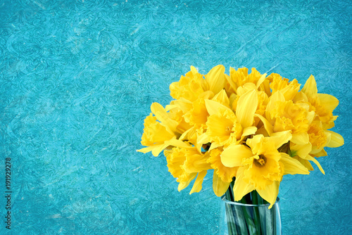 Fototapeta Naklejka Na Ścianę i Meble -  Bouquet of fresh spring narcissus in vase on bright blue background. Copy space