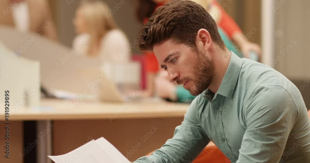 4K Businessman looking at company performance charts on tablet computer, with colleagues working in background. Slow motion. 4K Businessman looking at company performance charts on tablet computer, with colleagues working in background. Slow motion.