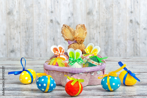 Happy Easter! Background with colorful eggs in basket and  on table.Surprise from the hare.
