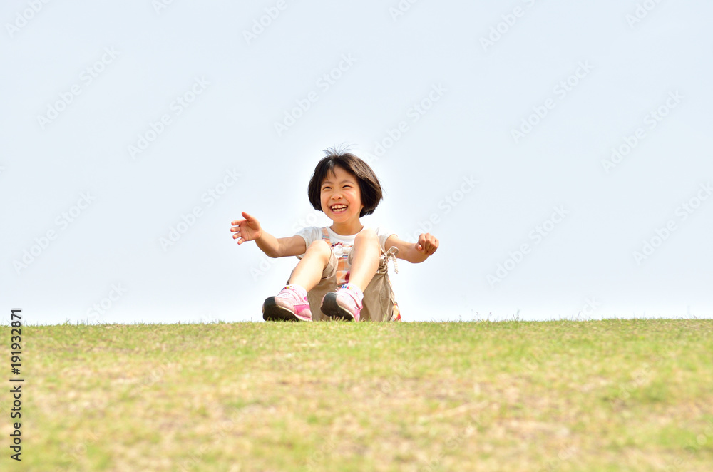 芝生広場で座る笑顔の女の子