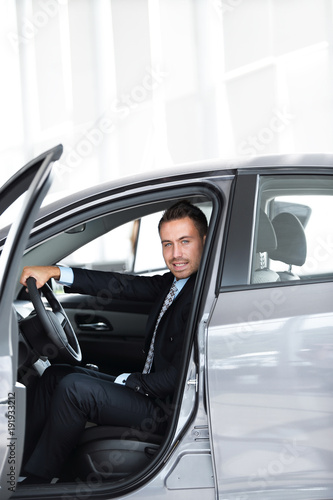 businessman sitting behind the wheel of a car, in the Parking lot at the car dealership