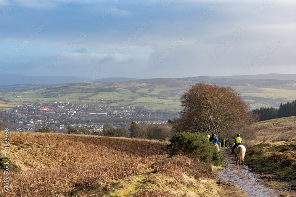 Horse riders making their way dow a wet trail 