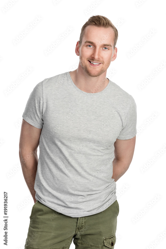 Handsome man in grey shirt smiling, standing against a white background indoors. Handsome man in grey shirt smiling, standing against a white background indoors.