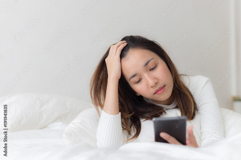 Happy women playing smartphone and smile on bed after wake up in the morning Happy women playing smartphone and smile on bed after wake up in the morning