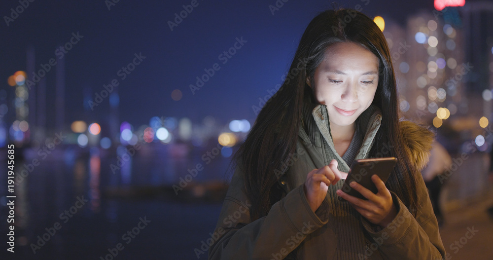 Woman using cellphone in city at night