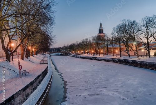 Beautiful view of Aura river at clear winter morning with street lights on and Turku Cathedral in the background