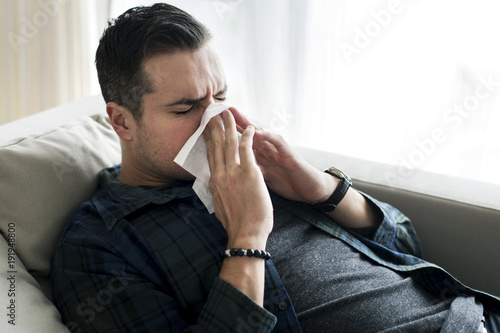 A sneezing Caucasian man on sofa