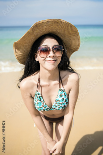 woman in bikini and straw hat stand on tropical beach