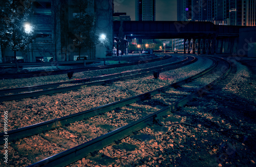 City downtown railway tracks with train bridge at night.