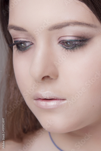 Fototapeta Naklejka Na Ścianę i Meble -  Girl with professional makeup and clean skin is looking down close-up