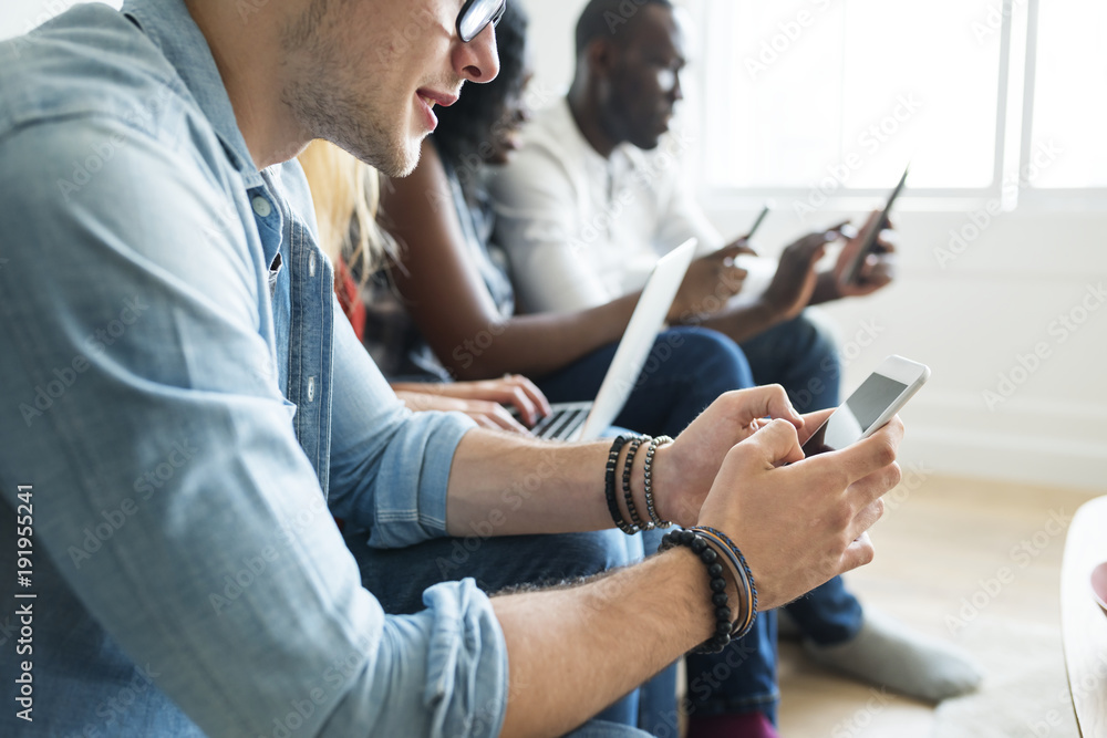 Group of diverse friends hanging out and using digital devices