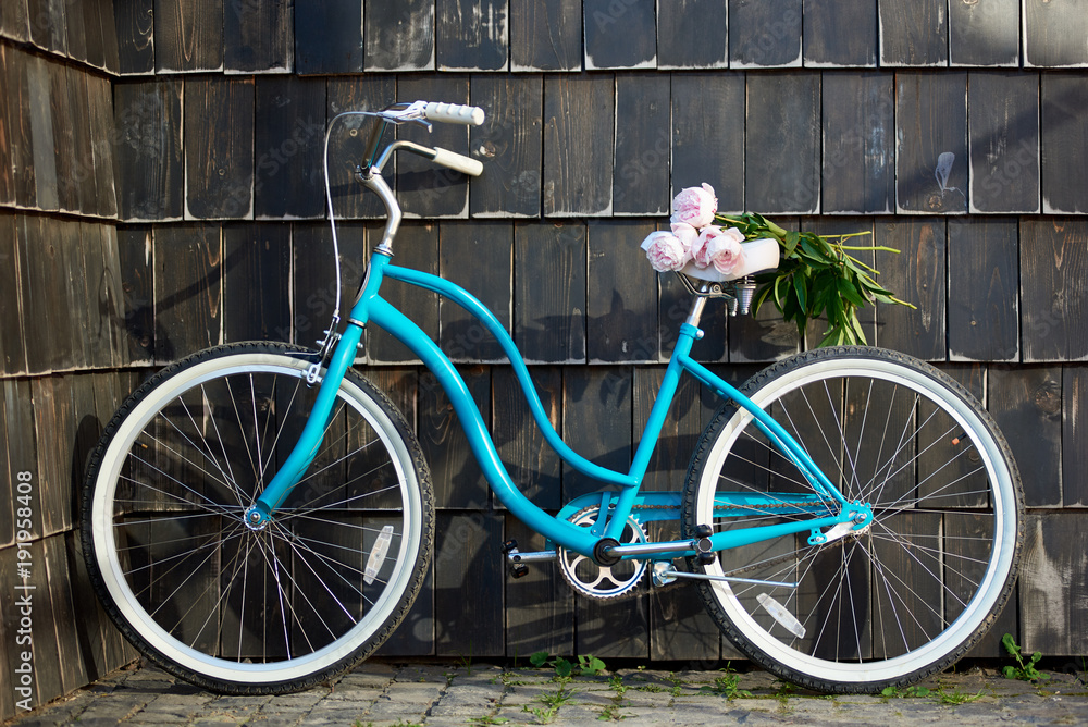 Shot of a blue city bicycle near the wall with a bunch of pink peonies on the seat copyspace flowers love romance romantic travelling memories tourism love transportation lifestyle.