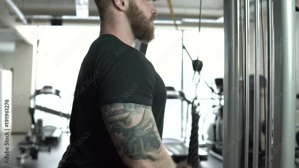 Athlete muscular bodybuilder training on a cable crossover fly pulley in the gym. Athlete muscular bodybuilder training on a cable crossover fly pulley in the gym.